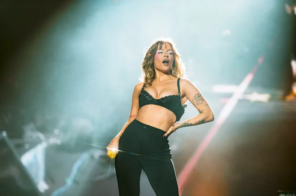 Luísa Sonza Chega ao Rock In Rio 2026 no Controle da Própria Narrativa 4 Luisa Sonza no palco The One do The Town 2025. Ela está com mão na cintura, vestindo jeans e sutiã pretos, meio inclinada para sua esquerda, segurando o microfone na mão direita e de boca aberta. Está com maquiagem forte, pegada no blush e com azul forte ao redor dos olhos.
