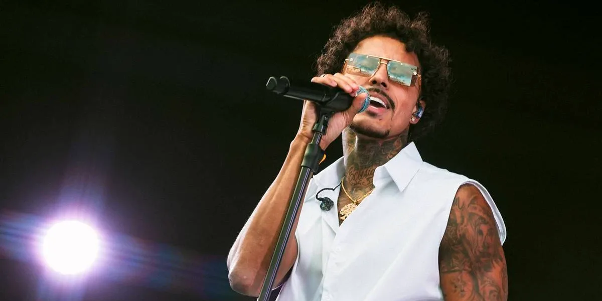 The Town 2025 | Palco Factory Anima o 4ª Dia do Festival Livinho com um colete branco, segurando o microfone com a mão direita, e rosto levemente inclinado no sentido oposto, de óculos no palco Factory do sábado do The Town 2025.