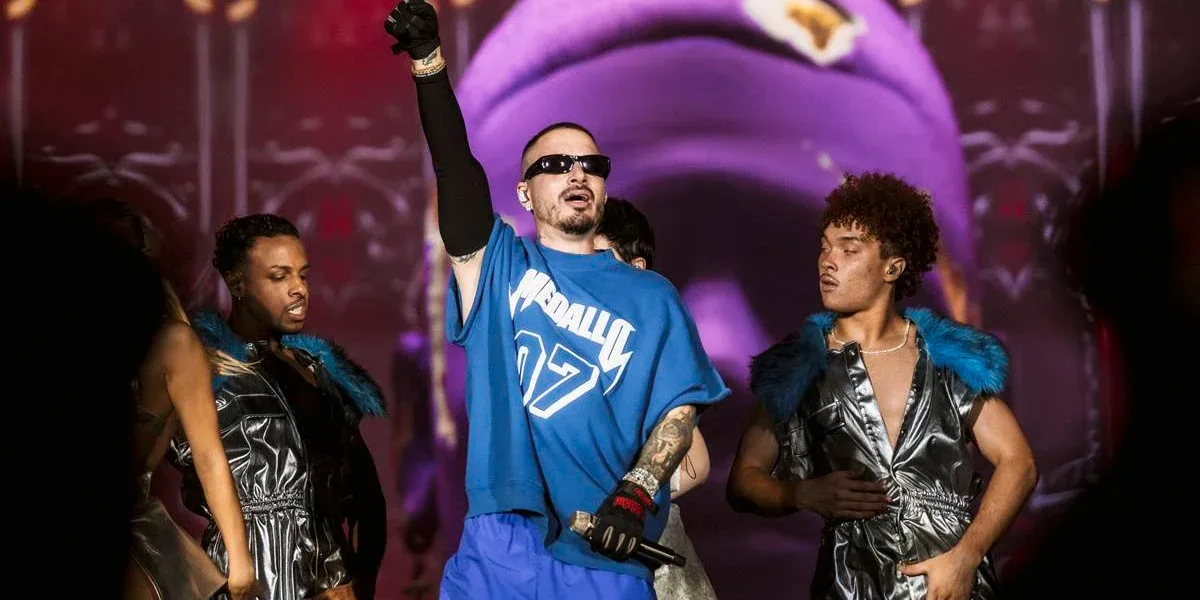 J Balvin, camiseta e calça azul, luva preta na mão estendida, óculos escuros, em apresentação no The Town 2025.