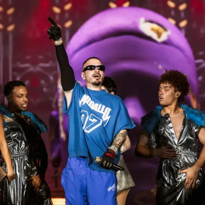 J Balvin, camiseta e calça azul, luva preta na mão estendida, óculos escuros, em apresentação no The Town 2025.