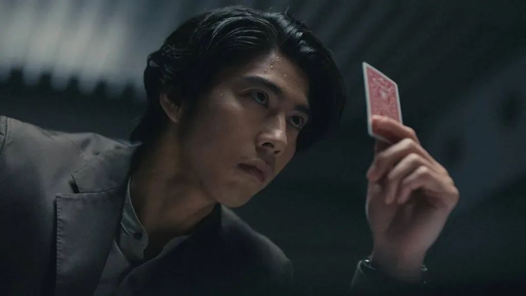 Kento Kako como o professor universitário Ryuuji, segurando uma carta na sua mão, capturado em contra-plongée, no primeiro episódio da terceira temporada de "Alice in Borderland".