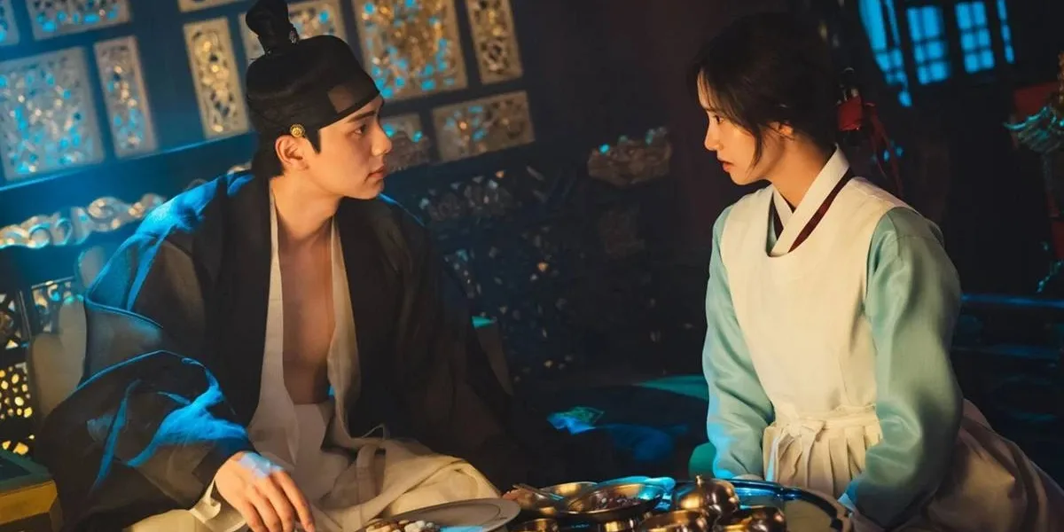 Lee Chae-min e Yoona como os protagonistas de "Bon Appétit, Vossa Majestade". Ele está com as roupas de rei de Joseon, Yi Heon, olhando para ela e vice-versa, e Yoona é Yeon Ji-young, cozinheira chefe real.