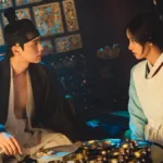 Lee Chae-min e Yoona como os protagonistas de "Bon Appétit, Vossa Majestade". Ele está com as roupas de rei de Joseon, Yi Heon, olhando para ela e vice-versa, e Yoona é Yeon Ji-young, cozinheira chefe real.