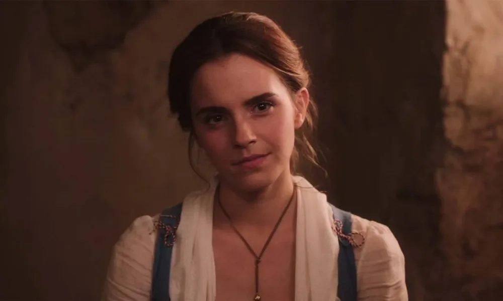 Emma Watson como a protagonista Bela de "A Bela e a Fera", live-action de 2017. Ela está com roupas de camponesa e um sorriso de canto de boca.