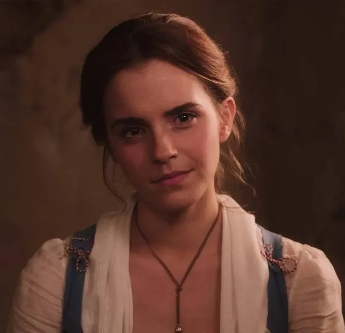 Emma Watson como a protagonista Bela de "A Bela e a Fera", live-action de 2017. Ela está com roupas de camponesa e um sorriso de canto de boca.