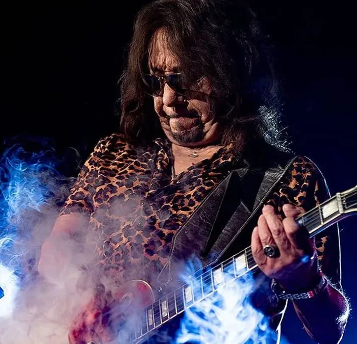 Ac Frehley tocando guitarra em show em 2025. Fumaça de glicerina pode ser vista no palco, ele com um semblante concentrado.
