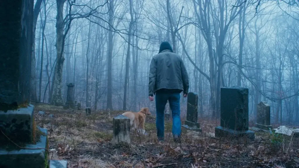 Bom Menino | Terror Para Cachorro Não Assusta Nem os Animais 2 Tod (Shane Jensen) ao lado do cão Indy em "Bom Menino". Ele está encapuzado em pé no cemitério da família.