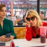 Júlia Rabello e Carolina Dieckmmann em "(Des)controle" em uma lanchonete. Imagem com cores vivas e a personagem de Carolina está afundando o rosto no braço, desanimada.