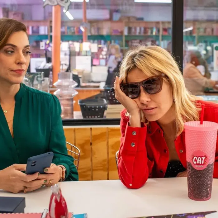 Júlia Rabello e Carolina Dieckmmann em "(Des)controle" em uma lanchonete. Imagem com cores vivas e a personagem de Carolina está afundando o rosto no braço, desanimada.