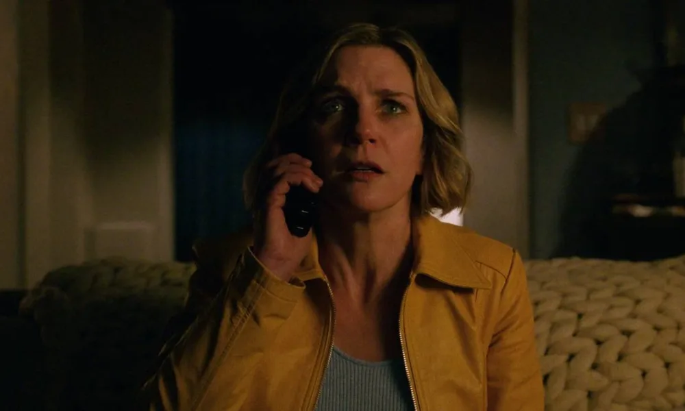 Rhea Seehorn como a protagonista de "Pluribus" com um telefone no ouvido e uma expressão de quem recebe uma notícia com espanto.