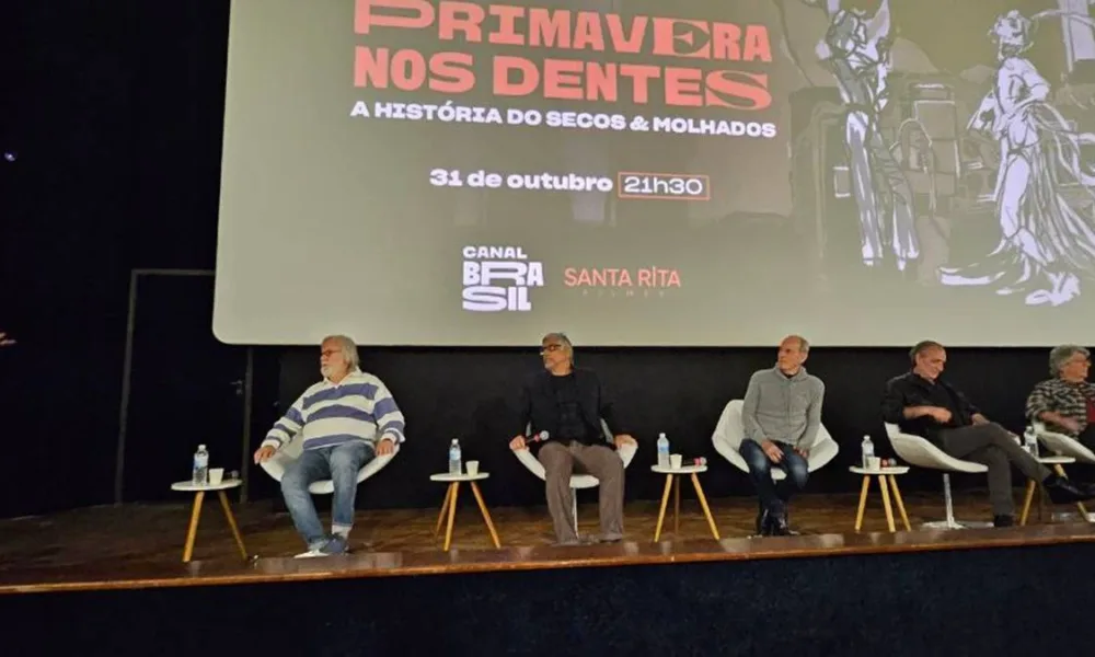 Foto horizontal do palco da coletiva de imprensa do lançamento da série "Primavera nos Dentes", documentário sobre o Secos & Molhados.