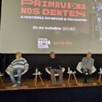 Foto horizontal do palco da coletiva de imprensa do lançamento da série "Primavera nos Dentes", documentário sobre o Secos & Molhados.