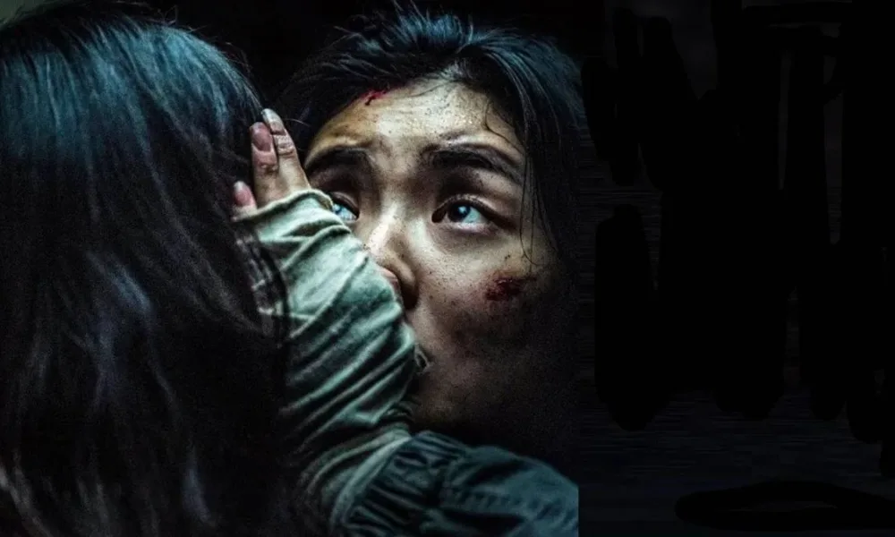 Protagonista de "Ruídos" (2025), segurando preocupada a cabeça de alguém, de costas para nós. O ambiente está todo escuro.