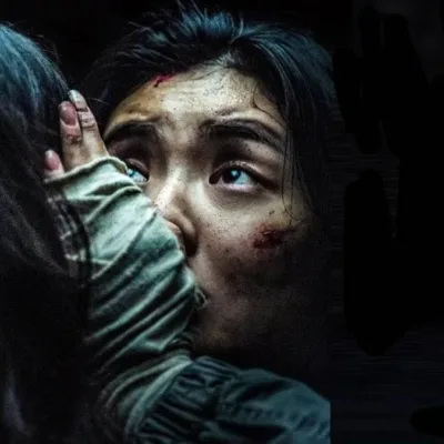 Ruídos | A Criatividade Praticamente Sem Limites do Cinema de Terror Asiático Protagonista de "Ruídos" (2025), segurando preocupada a cabeça de alguém, de costas para nós. O ambiente está todo escuro.
