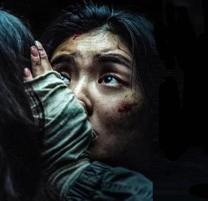 Protagonista de "Ruídos" (2025), segurando preocupada a cabeça de alguém, de costas para nós. O ambiente está todo escuro.