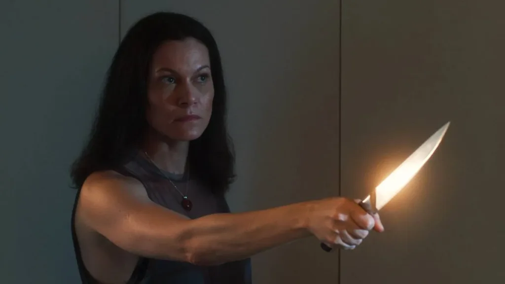 Gravidade | Às Vezes É No Fim de Tudo Que Nos Encontramos 1 Mulher empunhando uma faca em ameaça no filme "Gravidade", de 2025.
