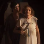 Imagem promocional do filme "Gravidade" (2025). Uma mulher à frente segura uma faca na altura do peito, enquanto outra está atrás dela, olhando para o mesmo ponto que ela, nosso ponto de vista de câmera.