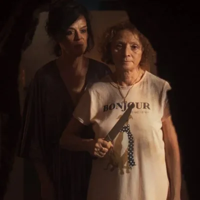 Imagem promocional do filme "Gravidade" (2025). Uma mulher à frente segura uma faca na altura do peito, enquanto outra está atrás dela, olhando para o mesmo ponto que ela, nosso ponto de vista de câmera.