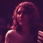 Fotografia em filtro vermelho arroxeado de Lô Borges na juventude.