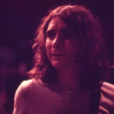 Fotografia em filtro vermelho arroxeado de Lô Borges na juventude.