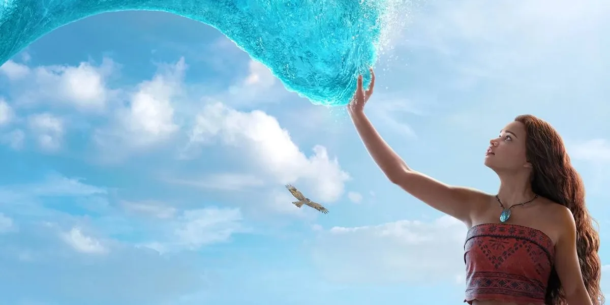 Catherine Laga‘aia como Moana no live action de 2026. Ela está no canto inferior direito tocando o mar que se move até ela como um tentáculo brilhante, ocupando a maior parte da tela.