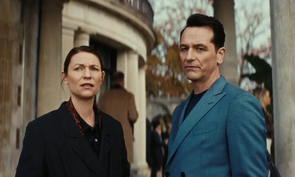 Claire Danes como Agatha 'Aggie' Wiggs e Matthew Rhys como Nile Jarvis, um ao lado do outro, olhando como se recalculassem a rota, de pé, na frente de um prédio de estrutura clássica na série "O Monstro em Mim".