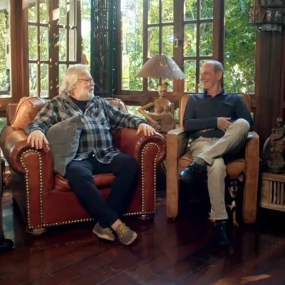 Gérson Conrad, Willy Verdaguer, Ney Matogrosso, cada um em uma poltrona, conversando e rindo durante filmagem do documentário "Primavera nos Dentes: a História dos Secos & Molhados".
