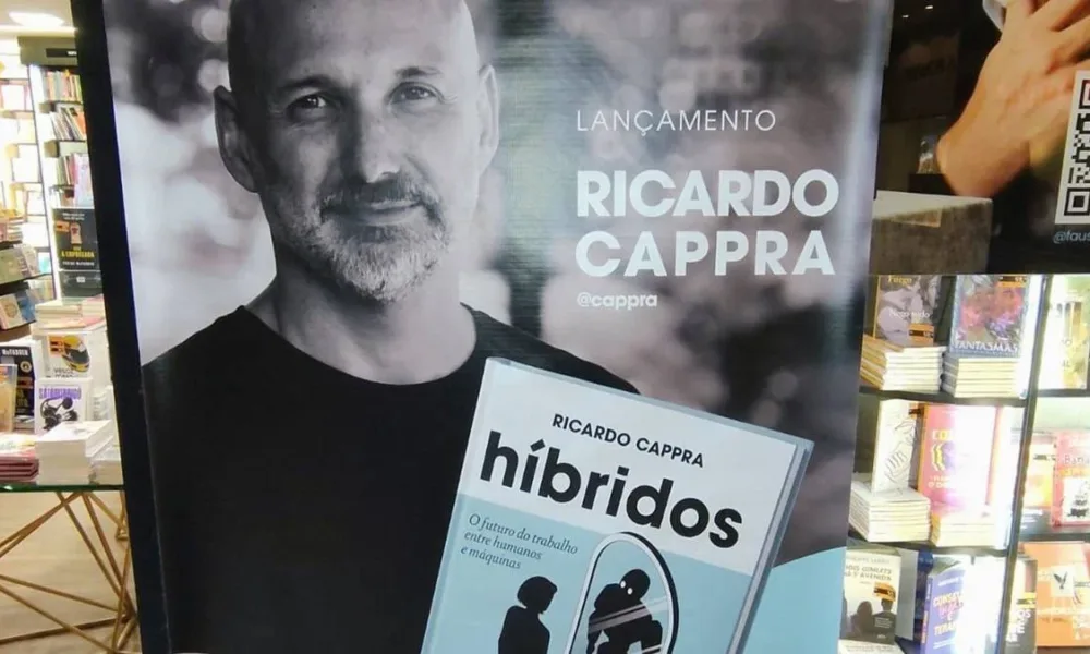 Pôster com autor Ricardo Cappra em matiz sépia segurando livro "Híbridos" em lançamento.