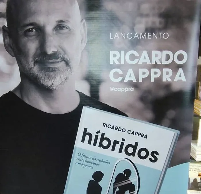 Pôster com autor Ricardo Cappra em matiz sépia segurando livro "Híbridos" em lançamento.
