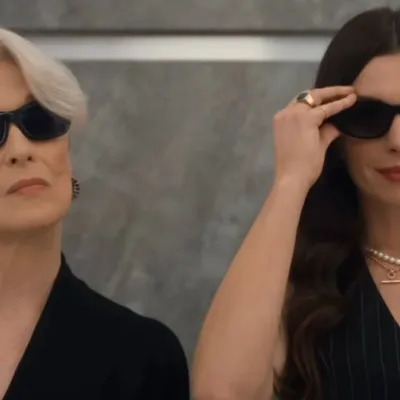 Meryl Streep (esquerda) e Anne Hathaway (direita) em elevador de óculos escuros reprisando os papéis de Miranda e Andy na continuação "O Diabo Veste Prada 2". Ambas estão de preto e câmera as pega do busto para cima.