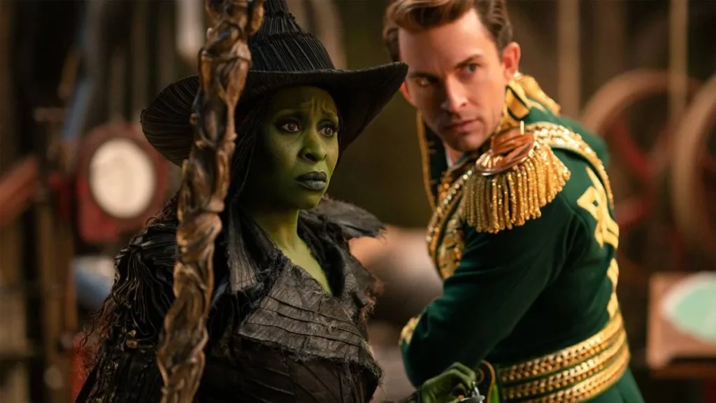 Cynthia Eriva como Elphaba, segurando sua vassoura, e Jonathan Bailey à direita ao fundo como Fiyero, ambos olhando para o mesmo ponto com aflição. Imagem da segunda parte (2025) de "Wicked".