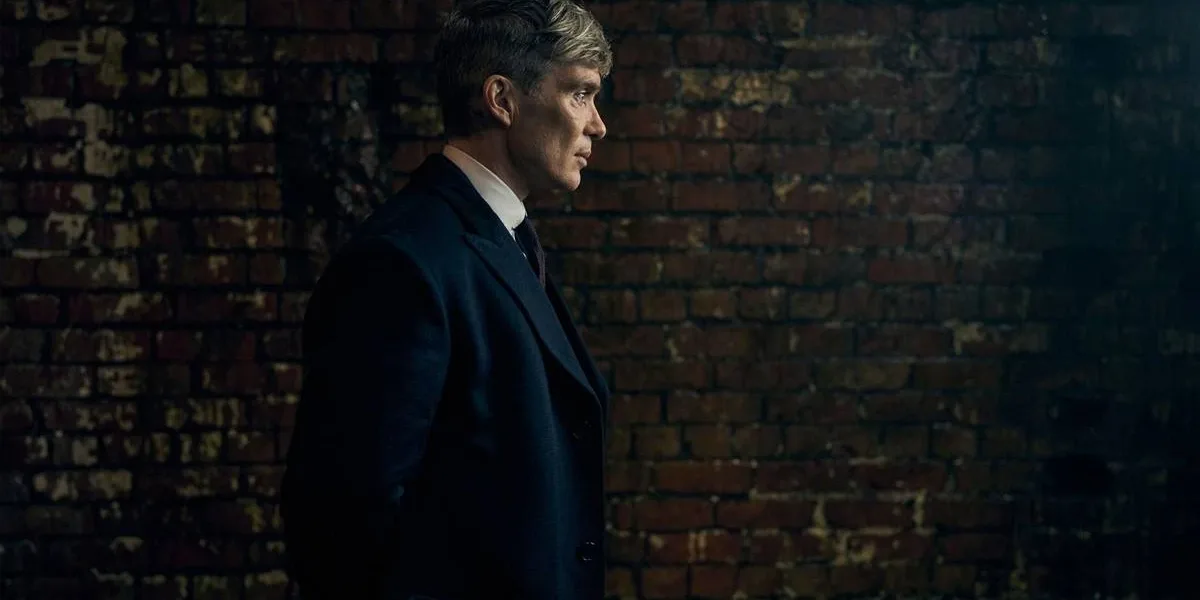 Peaky Blinders: O Homem Imortal | Netflix Lança Trailer do Fim da Saga Cillian Murphy caracterizado como Thomas Shelby para o filme de fechamento da franquia "Peaky Blinders", ambientado na 2ª Guerra Mundial, "O Homem Imortal". Ele está de perfil, mãos para trás, com um muro de tijolos ao fundo.
