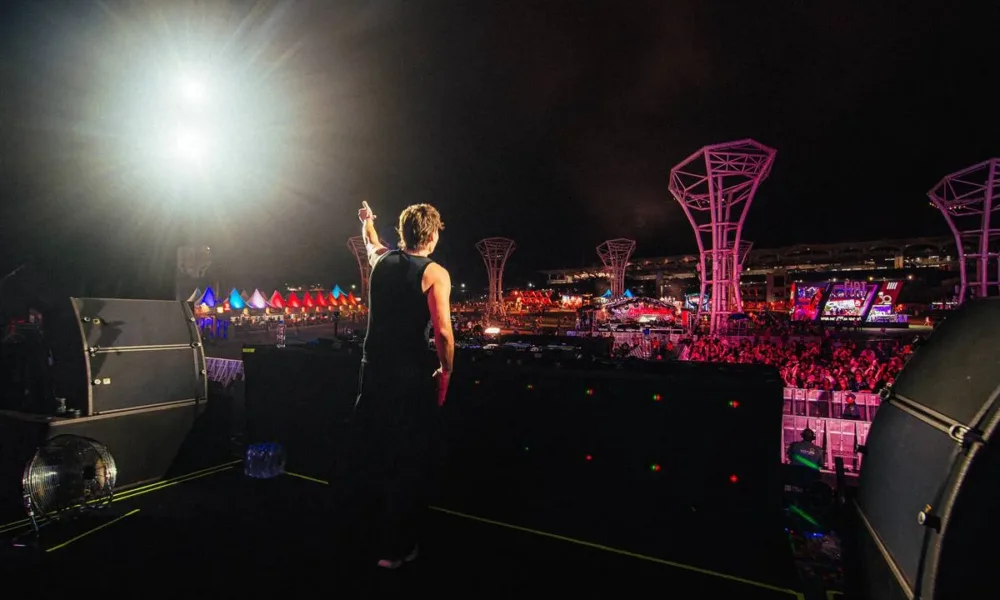 Bunt em fotografia tirada de costas com artista acenando para plateia no palco Perry's do Lollapalooza 2026.