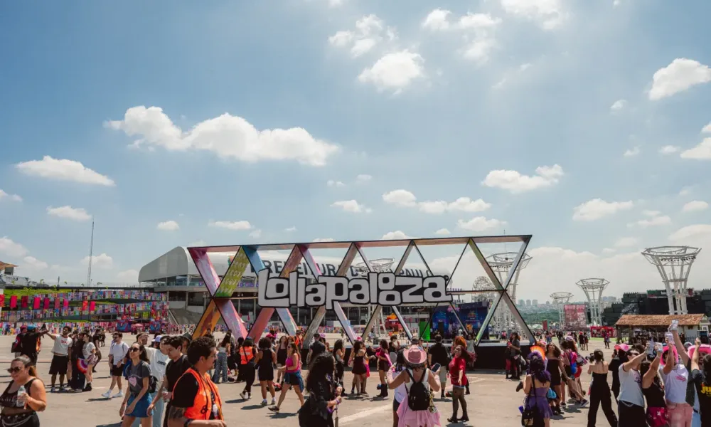 Estrutura de escultura com o logo do Lollapalooza com público passando pela praça no sábado do evento em 2026.
