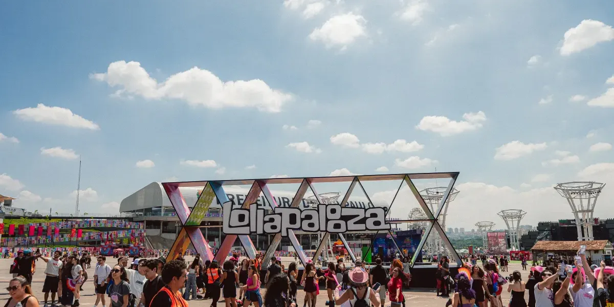 Estrutura de escultura com o logo do Lollapalooza com público passando pela praça no sábado do evento em 2026.