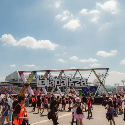 Estrutura de escultura com o logo do Lollapalooza com público passando pela praça no sábado do evento em 2026.