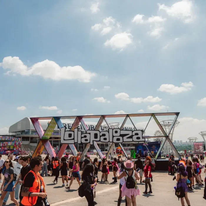 Estrutura de escultura com o logo do Lollapalooza com público passando pela praça no sábado do evento em 2026.