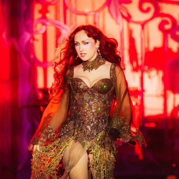 Chappell Roan durante apresentação, maquiada como drag, em palco no Lollapalooza 2026 no Brasil em tonalidade vermelha e cheio de brilho.