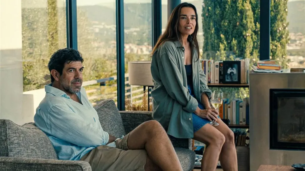 Pais do protagonista Enzo no filme "Enzo", Paolo e Marion, interpretados por Pierfrancesco Favino e Élodie Bouchez, sentados em um sofá em uma casa abastada com vista da montanha.