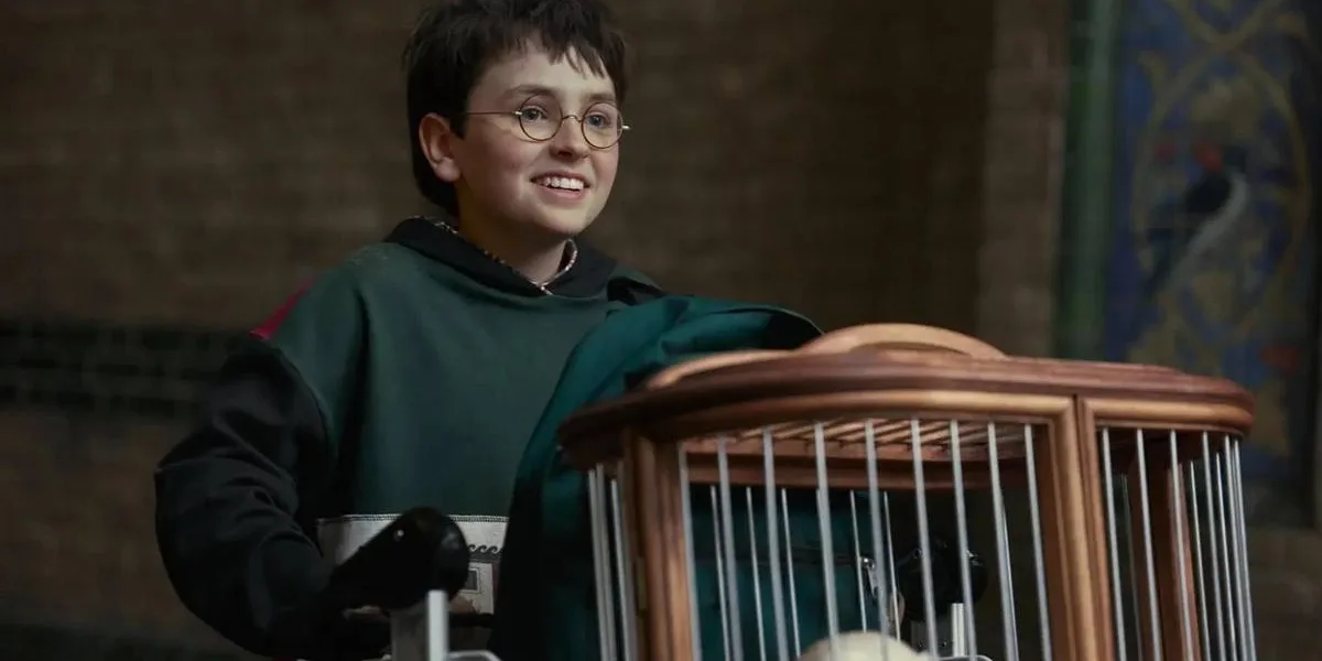 Dominic McLaughlin no primeiro trailer da série de "Harry Potter", da HBO. Ator mirim está vestido de verde, com luvas, e empurra um carrinho com seus pertences, sorrindo, na plataforma 9 3/4.