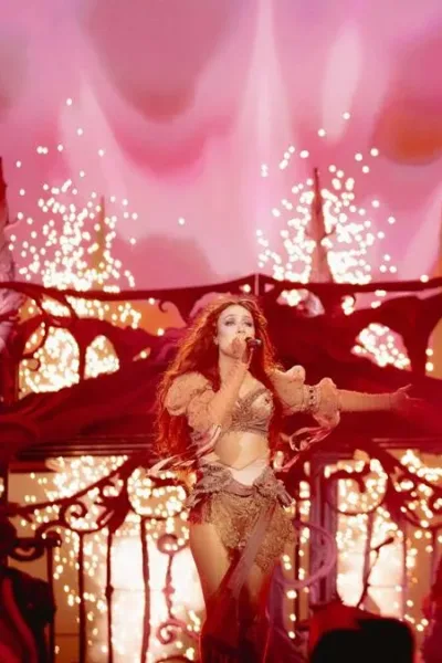 Chappell Roan durante apresentação, maquiada como drag, em palco em tonalidade vermelha e cheio de brilho.