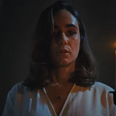 Alicia Sanz como a protagonista Natalie Flores em 'Push: no Limite do Medo', em cena do filme tensa segurando uma vela com a mão esquerda (à nossa direita) iluminando seu rosto no escuro.