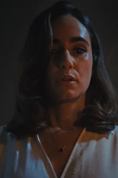 Alicia Sanz como a protagonista Natalie Flores em 'Push: no Limite do Medo', em cena do filme tensa segurando uma vela com a mão esquerda (à nossa direita) iluminando seu rosto no escuro.