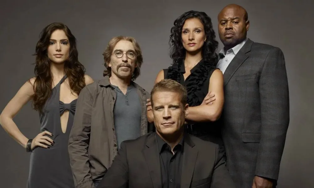 Elenco de "Screener: Alvo Humano" com protagonista ao centor centado, enquanto o resto do elenco está em pé posando para foto promocional em fundo cinza caracterizados como seus personagens na série.