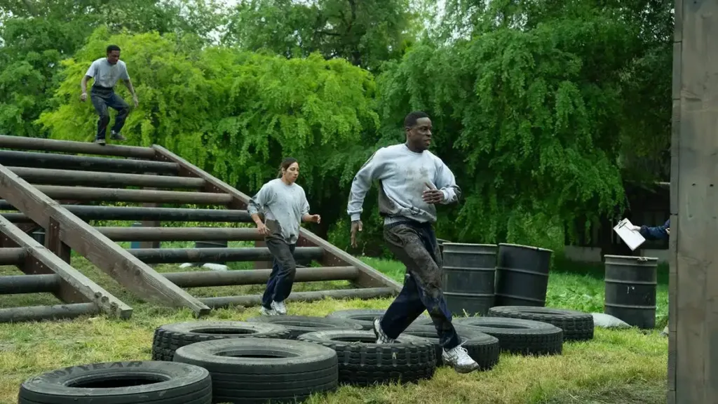 Paradise – 2ª Temporada | Com Nova Temporada Série da Disney+ Traz Novos Personagens e Outra Reviravolta 1 Sterling K. Brown como Xavier Collins na temporada 2, episódio 2, de "Paradise". Ele está com roupas de treinamento, correndo uma pista de obstáculos sobre um pneu ao lado de outras pessoas em cenário de floresta.