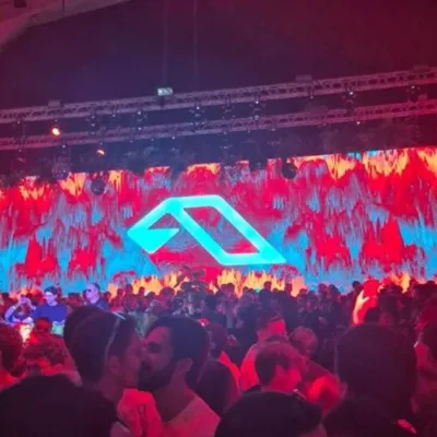 Foto do primeiro Anjuna Deep Open Air em São Paulo, 2026. Luzes vermelhas no ambiente, telão ao fundo, público aglomerado.