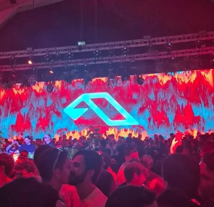 Foto do primeiro Anjuna Deep Open Air em São Paulo, 2026. Luzes vermelhas no ambiente, telão ao fundo, público aglomerado.