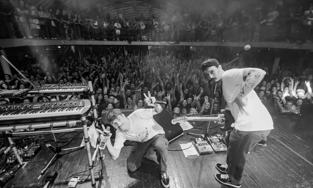 Fotografia em preto e branco com ponto de vista de trás do palco com grupo Braza em apresentação no Circo Voador.