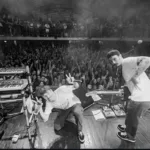 Fotografia em preto e branco com ponto de vista de trás do palco com grupo Braza em apresentação no Circo Voador.