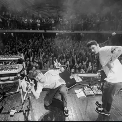 Fotografia em preto e branco com ponto de vista de trás do palco com grupo Braza em apresentação no Circo Voador.
